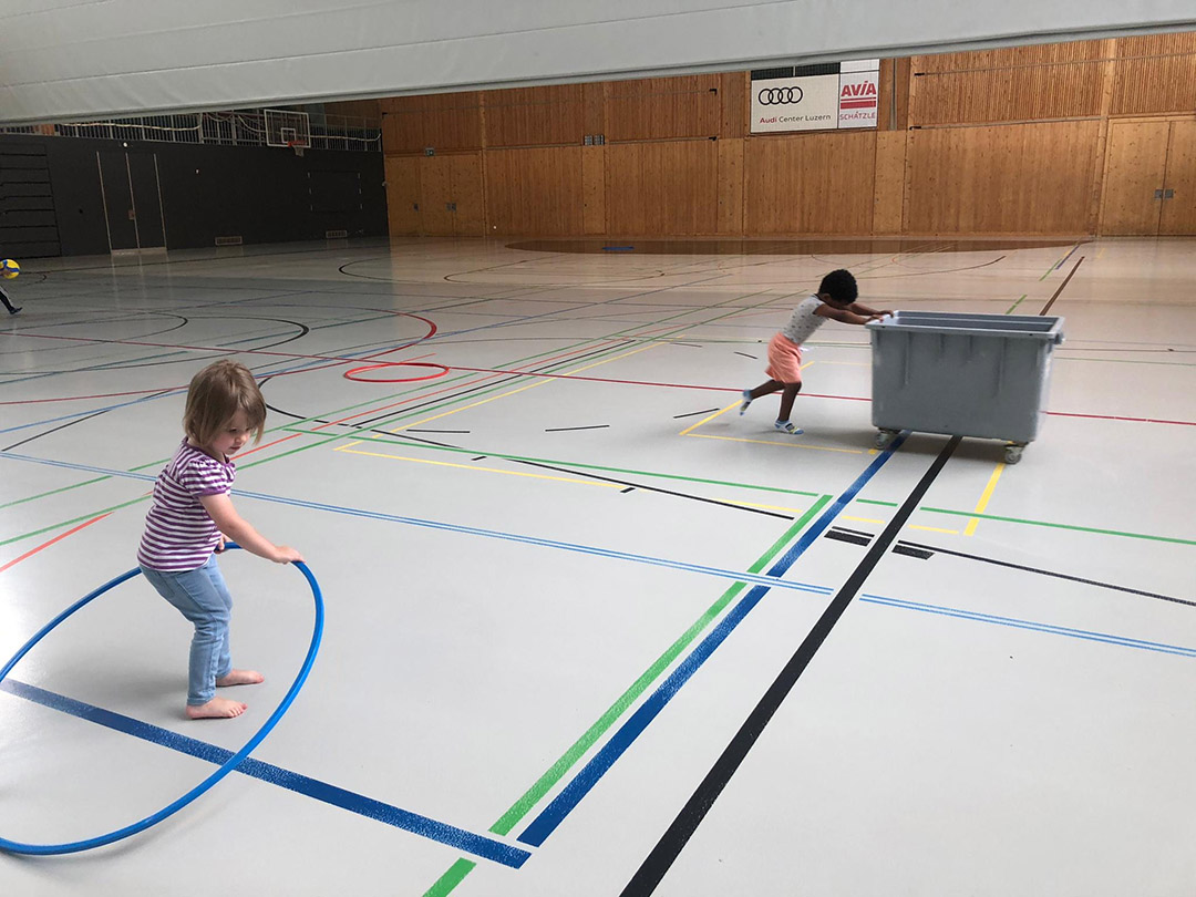 Kind bewegen sich mit Hulahop Ring und Ballkiste in der Turnhalle beim Besuch mit der Kinderkrippe Stärnschnuppe